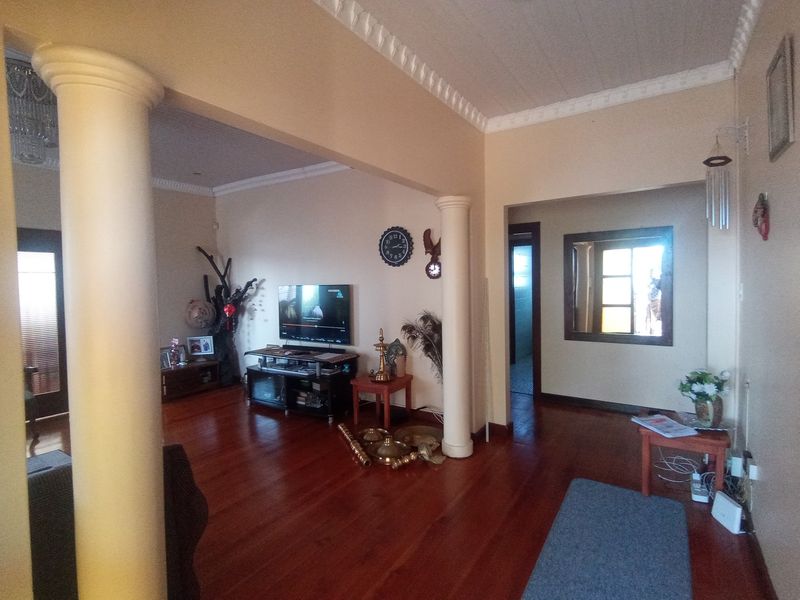Spacious living area featuring polished hardwood flooring, decorative crown molding, and architectural columns defining the open-plan layout.