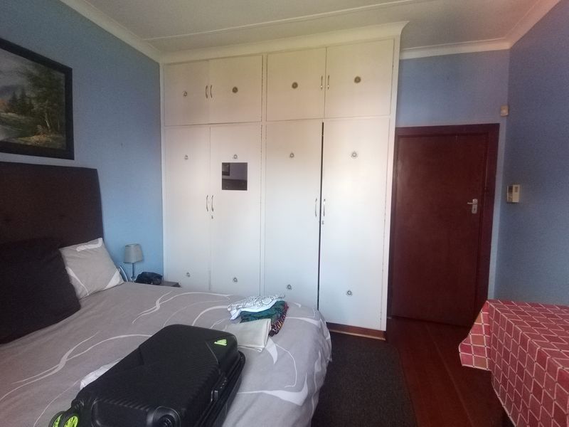 A bedroom featuring built-in cupboards, coving, and timber flooring.