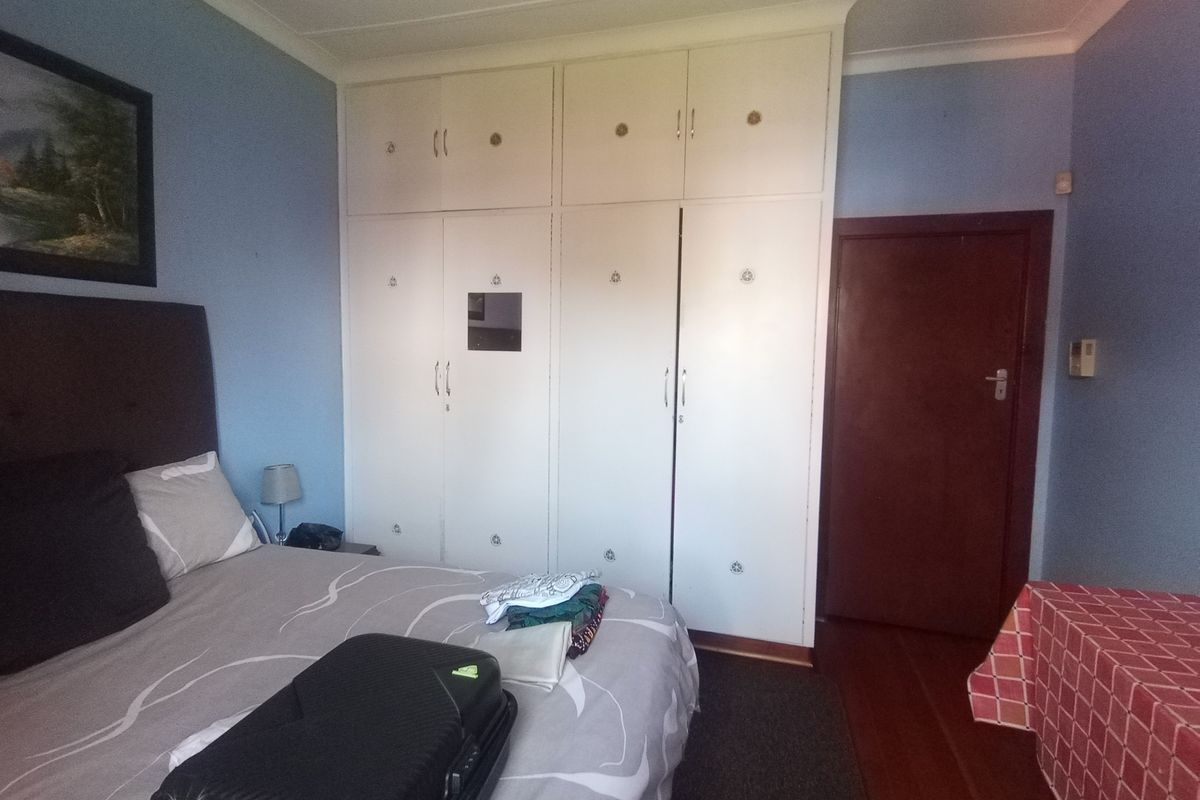 A bedroom featuring built-in cupboards, coving, and timber flooring.