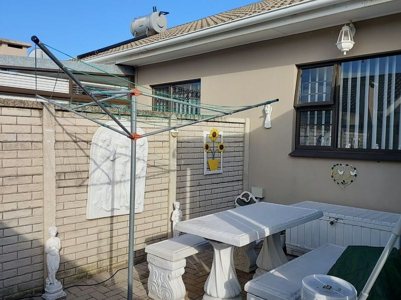 A rear courtyard area featuring paved flooring, brick boundary walls, and a solar water heater mounted on the tiled roof.