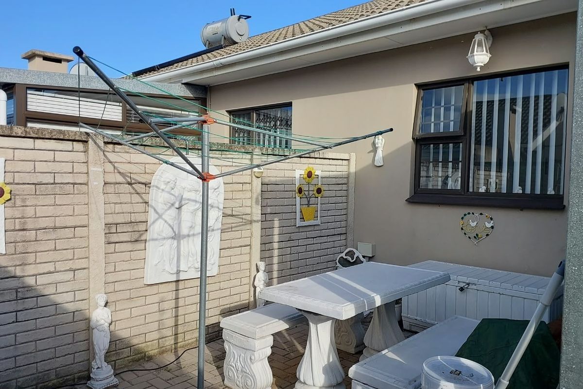 A rear courtyard area featuring paved flooring, brick boundary walls, and a solar water heater mounted on the tiled roof.