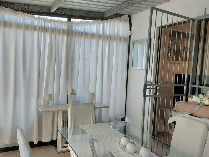 Enclosed patio area featuring tiled flooring, large windows, and a metal security gate, providing a versatile transition space between indoor and outdoor areas.