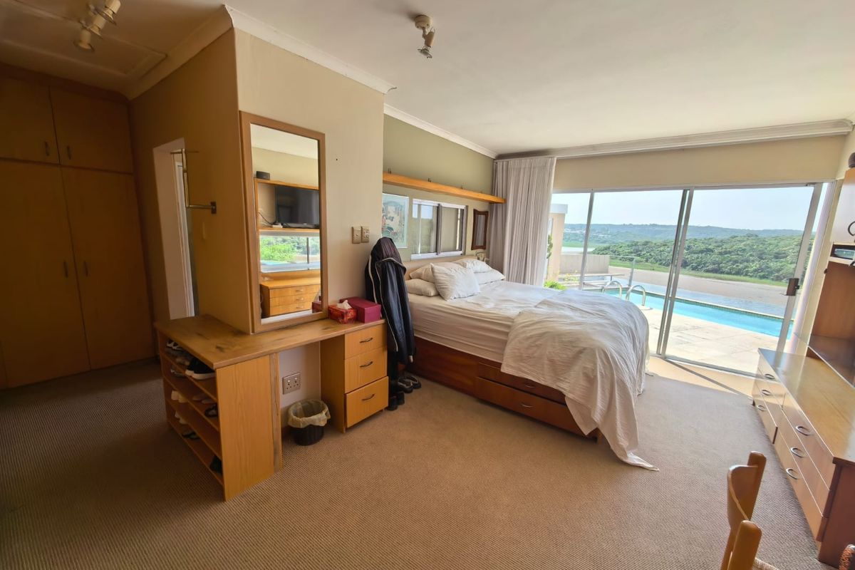 Spacious bedroom featuring built-in cupboards, carpeted flooring, and large sliding glass doors providing direct access to the pool area and scenic views.