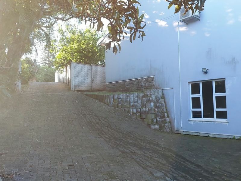 A view of the paved driveway leading up to the side of the house, featuring a retaining wall and exterior wall finishes.