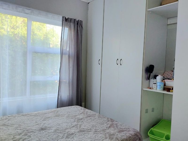 A bedroom featuring built-in cupboards and a large window allowing natural light.