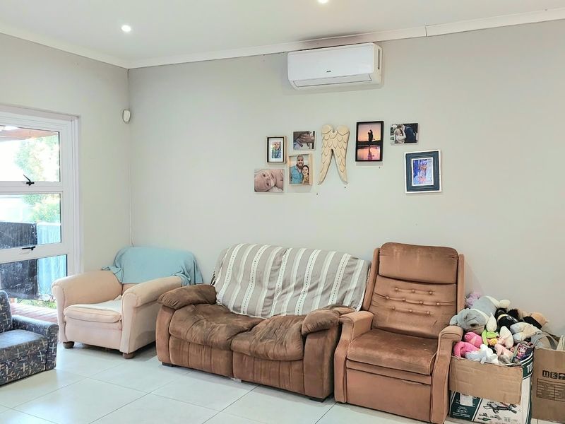 A living room featuring tiled flooring, recessed lighting, and a wall-mounted air conditioning unit, with direct access to an outdoor patio area.