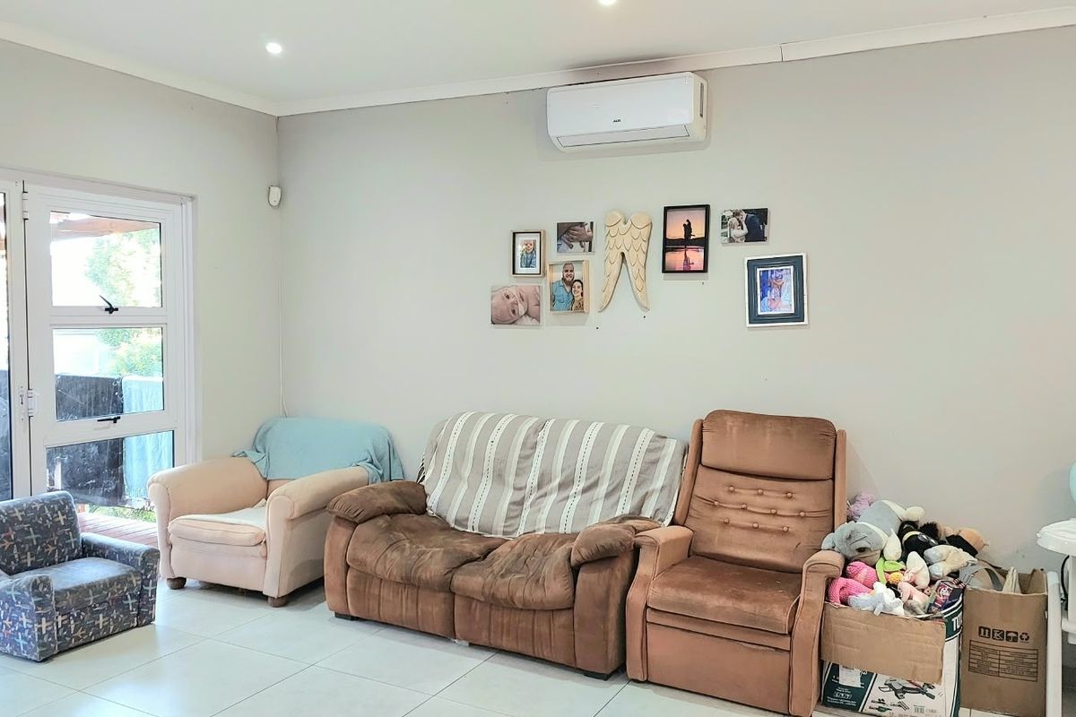 A living room featuring tiled flooring, recessed lighting, and a wall-mounted air conditioning unit, with direct access to an outdoor patio area.