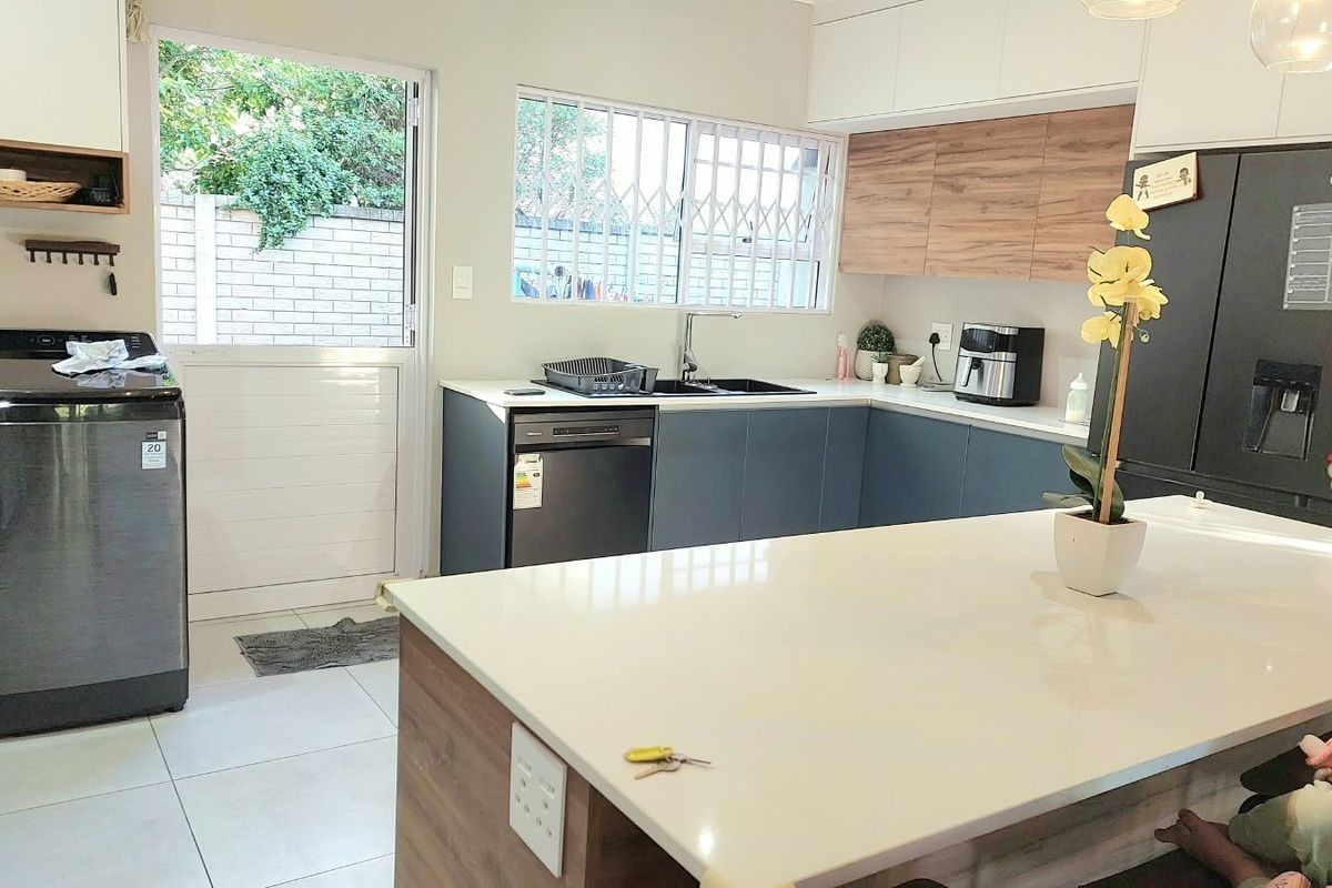 Modern kitchen featuring a central island with quartz countertops, sleek cabinetry, and direct access to the exterior through a secure door.