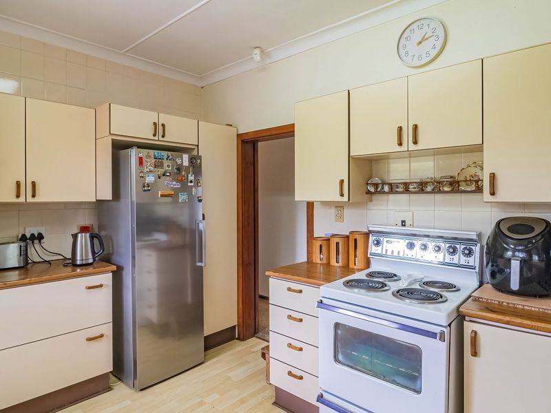 A functional kitchen featuring laminate cabinetry, tiled backsplash, and a freestanding electric stove with oven, offering a classic, dated aesthetic.