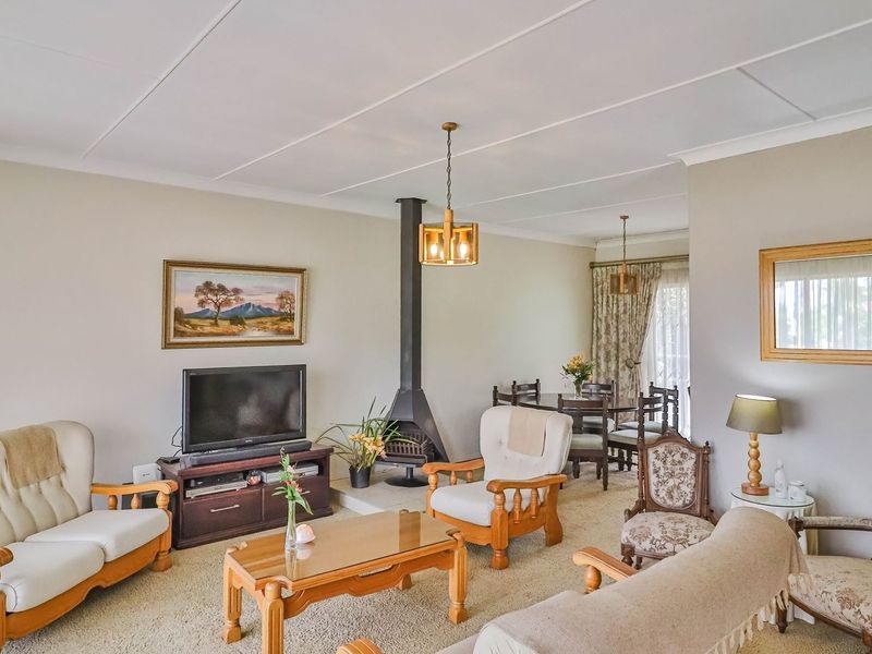 Open plan living and dining area featuring a central freestanding fireplace, neutral wall finishes, and carpeted flooring with access to the outdoor area.