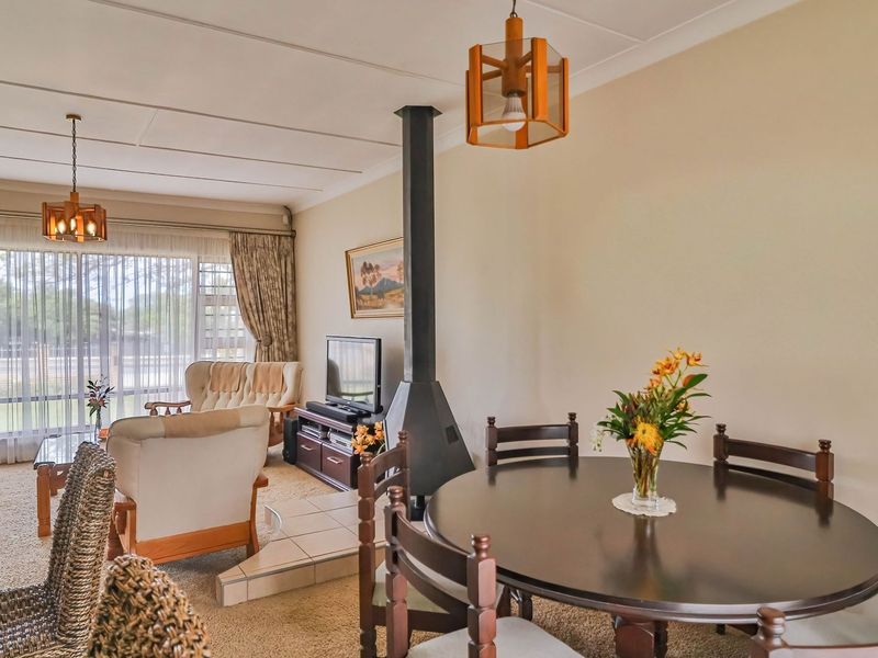 Open plan living and dining area featuring a central freestanding fireplace with a tiled hearth and large windows providing natural light.