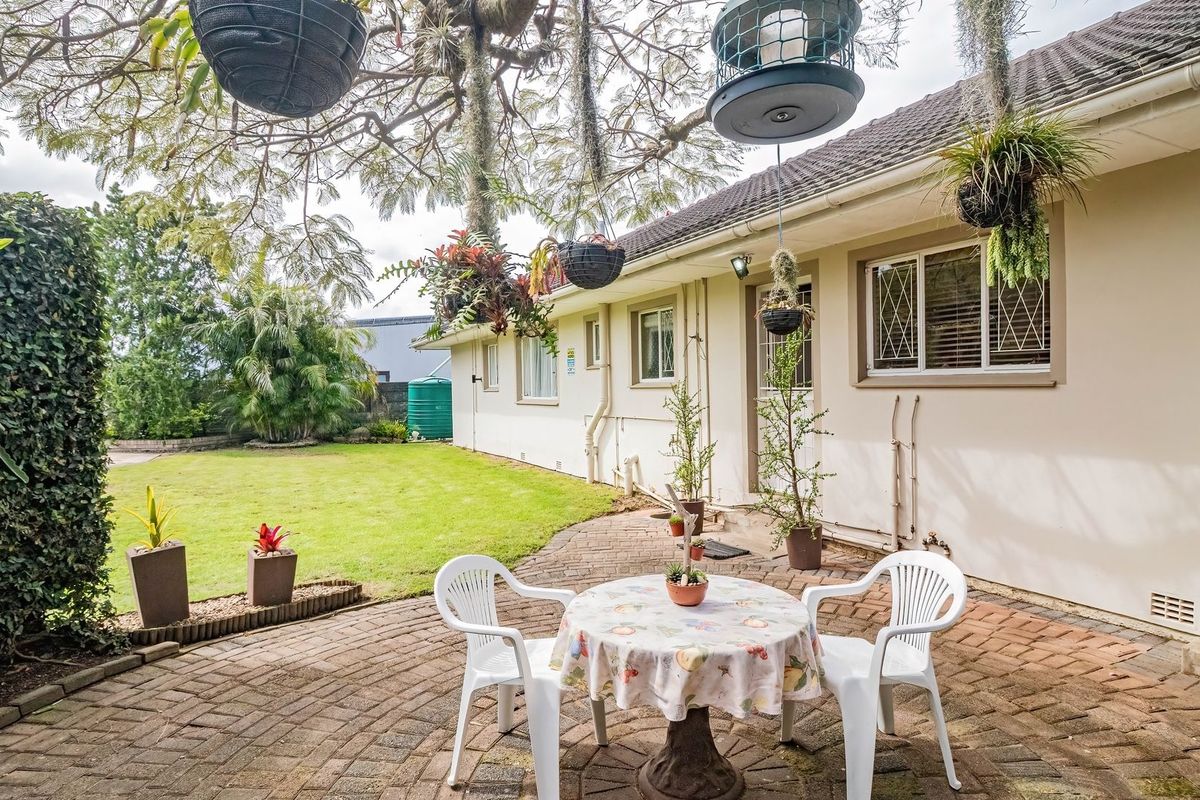 A well-maintained rear exterior featuring a brick-paved patio area, established lawn, and secure window fixtures, providing a pleasant outdoor living space.