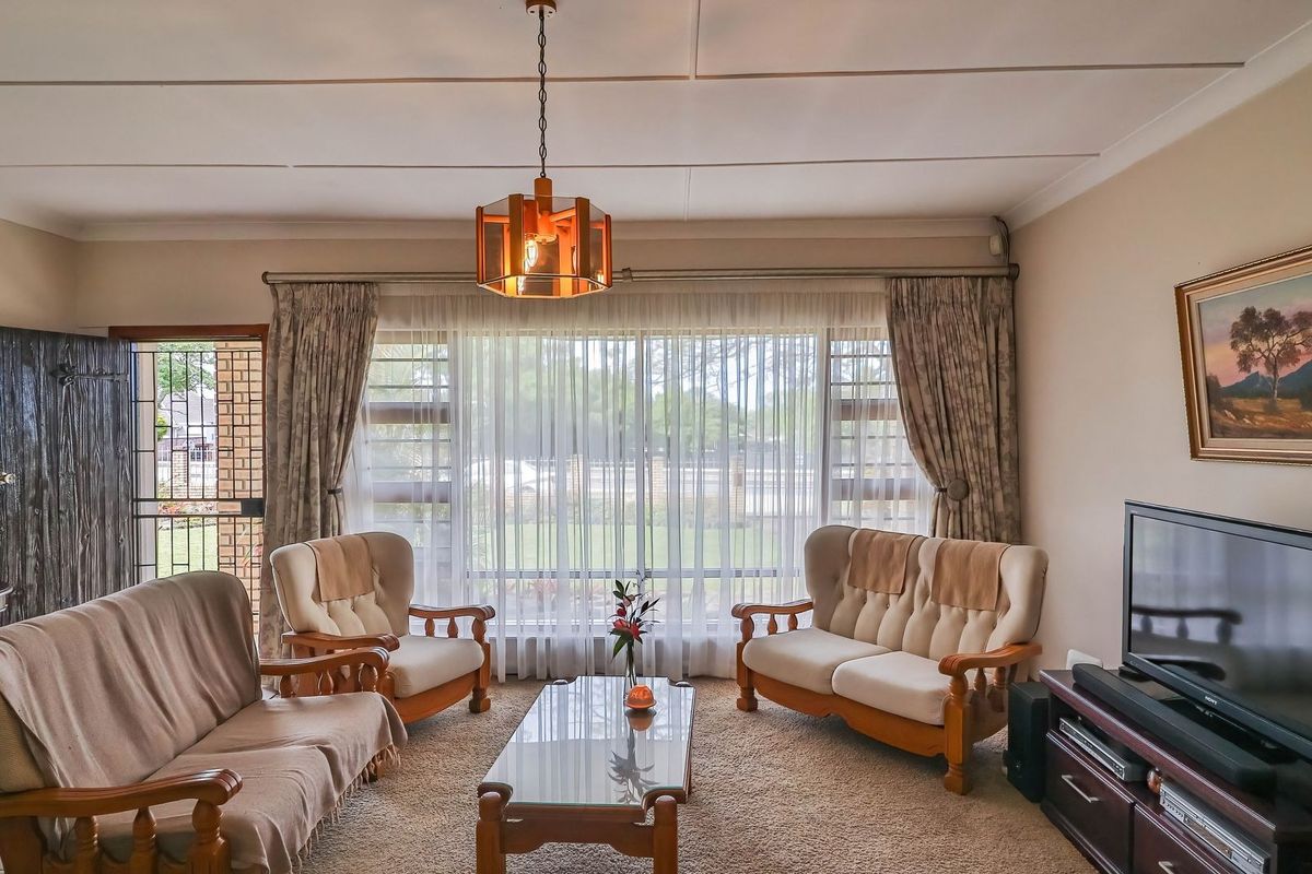 A comfortable living room featuring large windows, tiled flooring, and a classic ceiling finish, offering a bright and functional space.
