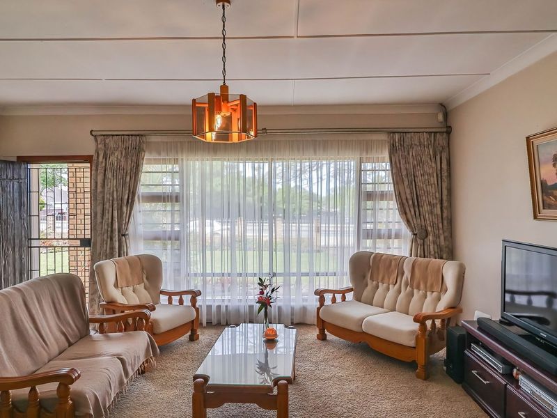A comfortable living room featuring large windows, tiled flooring, and a classic ceiling finish, offering a bright and functional space.