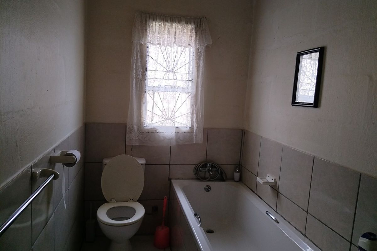 A functional bathroom featuring a bathtub, toilet, and tiled wall finishes, requiring cosmetic updates to modernize the space.