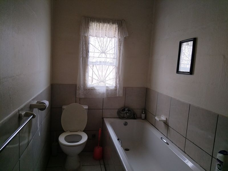 A functional bathroom featuring a bathtub, toilet, and tiled wall finishes, requiring cosmetic updates to modernize the space.