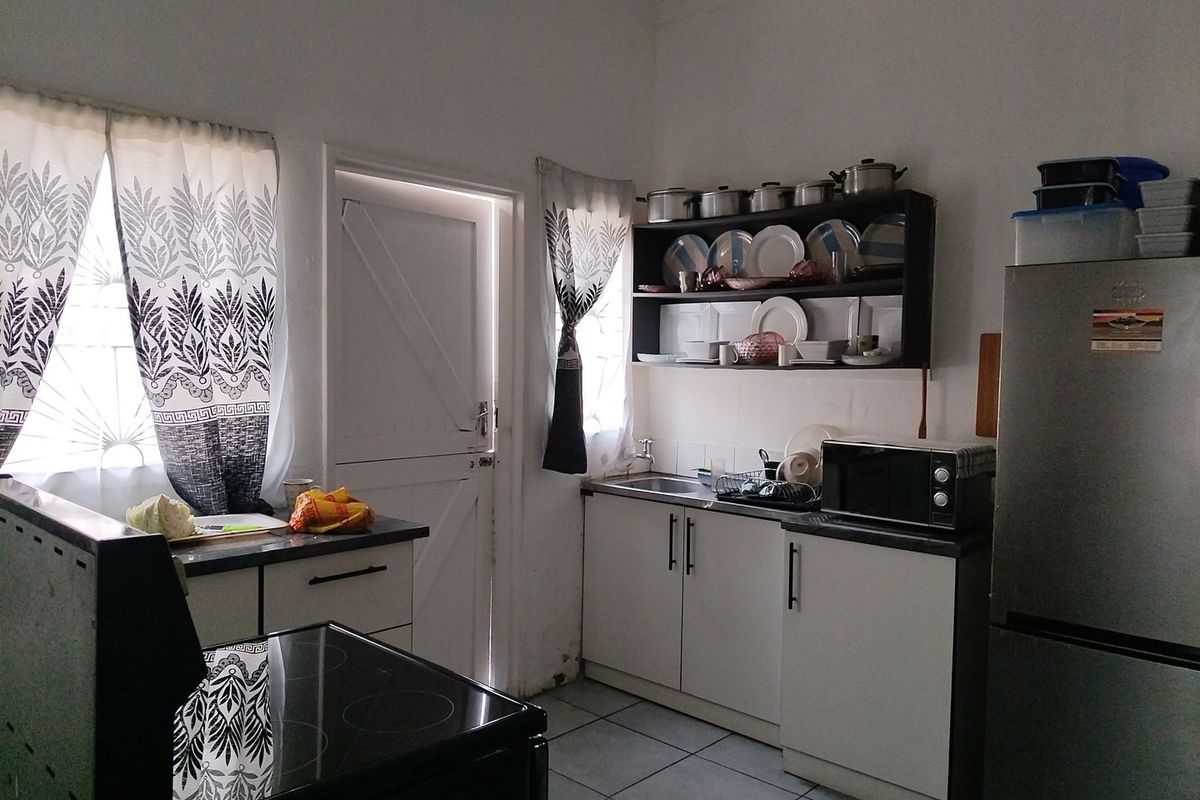 A functional kitchen featuring built-in cabinetry, open shelving, a sink, and tiled flooring, providing a practical workspace for daily meal preparation.