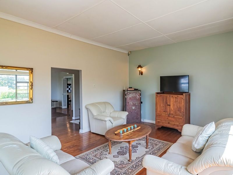 A spacious living room featuring hardwood flooring, coved ceilings, and wall-mounted lighting, providing a comfortable and functional living space.