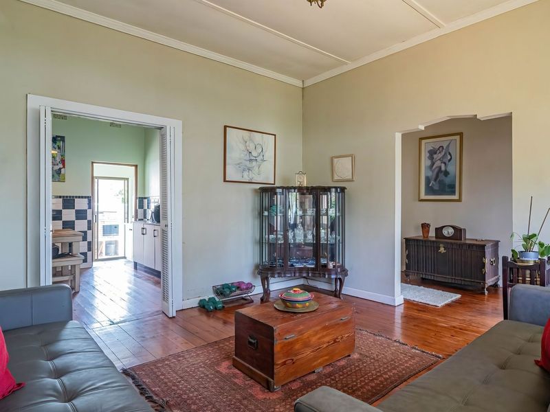 A spacious living room featuring polished hardwood flooring, classic crown molding, and an open archway leading to an adjacent room.