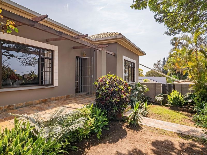 A well-maintained rear exterior featuring a tiled patio, timber pergola, and established garden area with secure access.