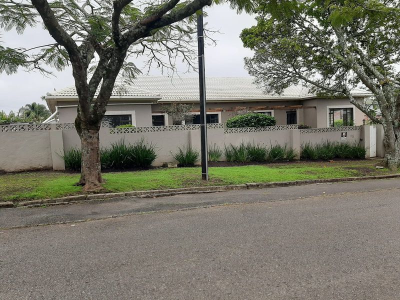 Front view of a single-story house featuring a tiled roof, perimeter wall with decorative breeze blocks, and established garden landscaping.