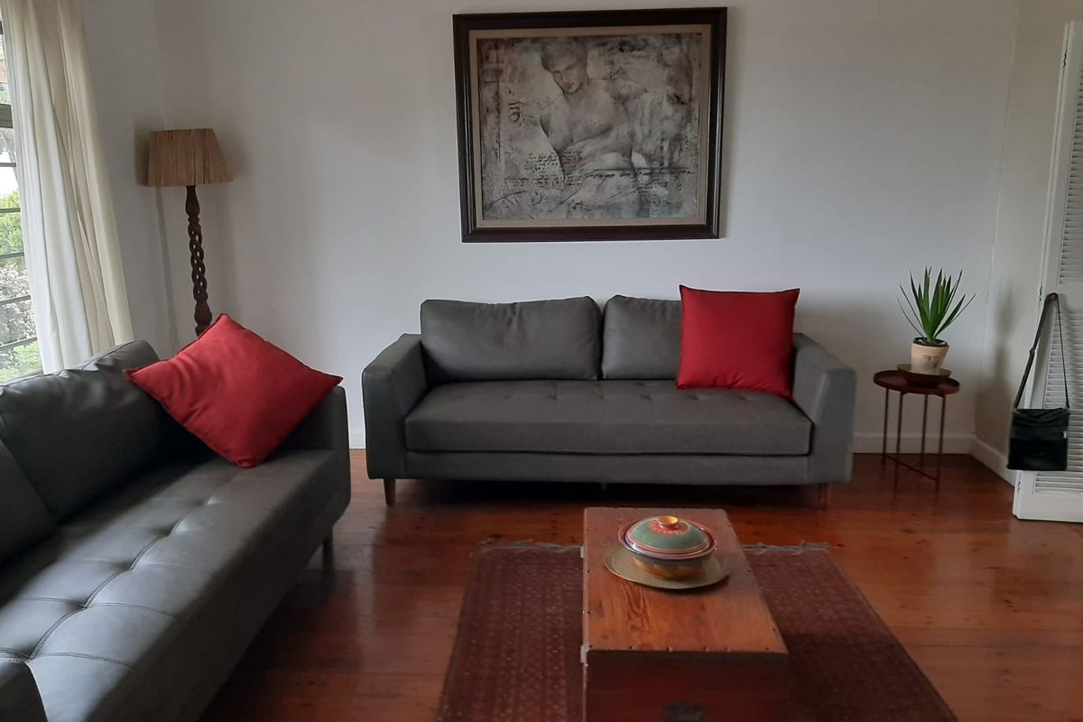 A comfortable living room featuring polished hardwood flooring and a classic louvered door, providing a warm and inviting atmosphere.