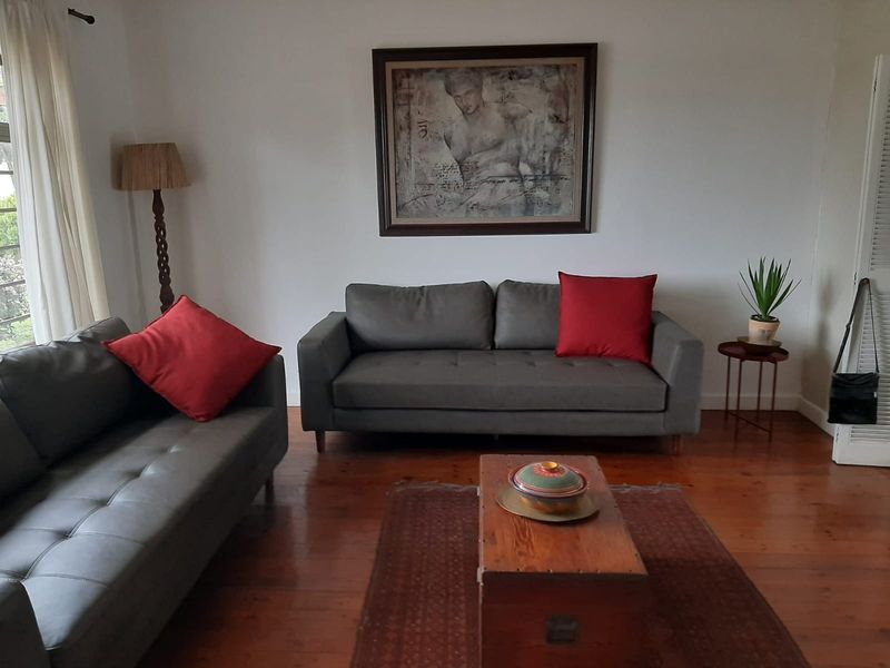 A comfortable living room featuring polished hardwood flooring and a classic louvered door, providing a warm and inviting atmosphere.