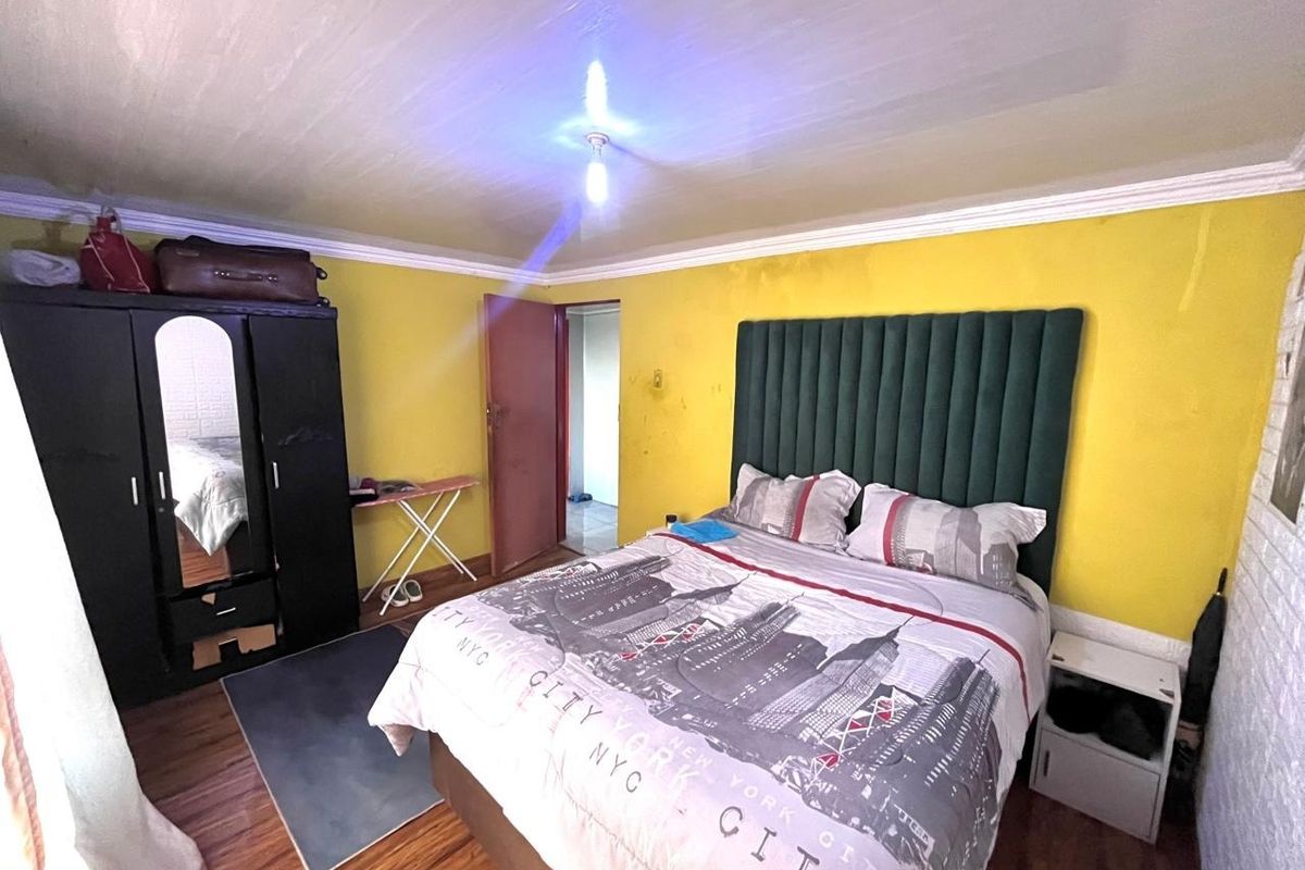 A bedroom featuring laminate flooring and crown molding, currently finished with bright yellow wall paint.