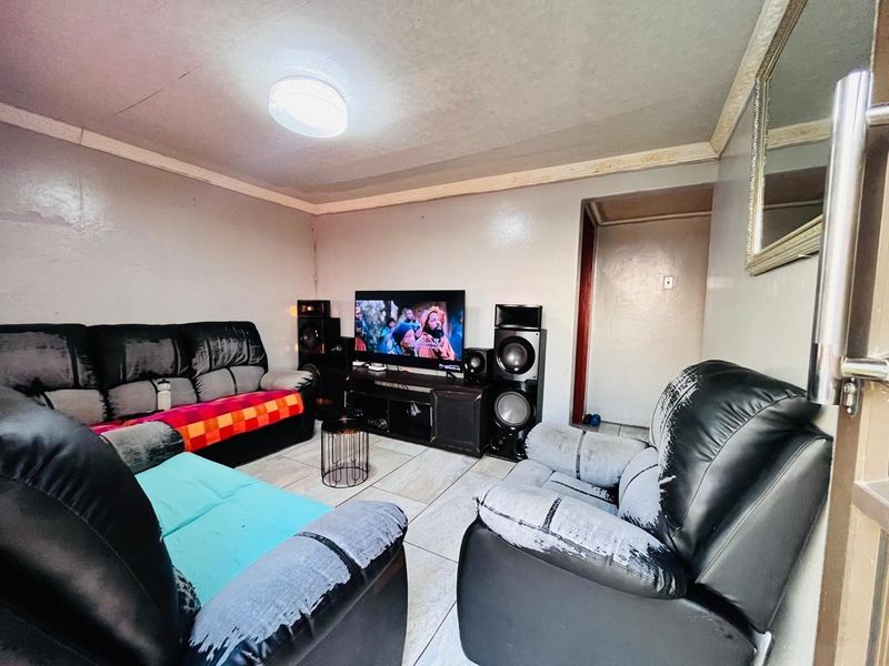 A living room featuring tiled flooring and ceiling cornice, currently showing signs of wear on the walls requiring maintenance and cosmetic updates.