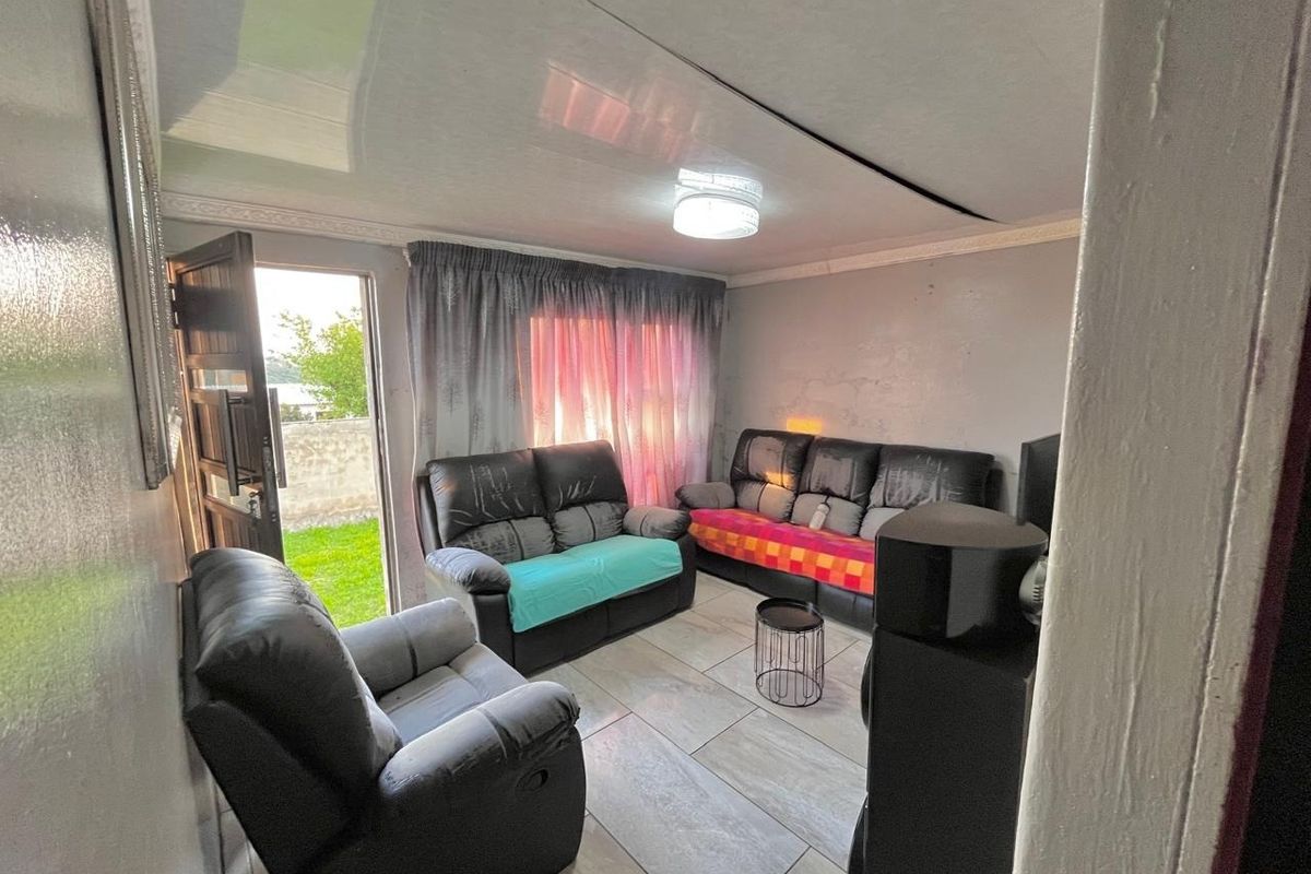 A living room featuring tiled flooring, a ceiling light fixture, and direct access to the exterior through a door.