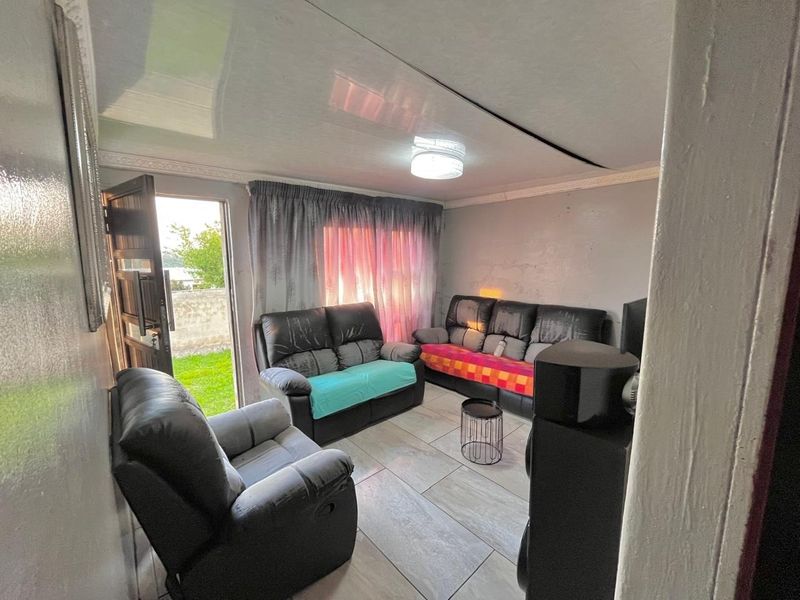 A living room featuring tiled flooring, a ceiling light fixture, and direct access to the exterior through a door.