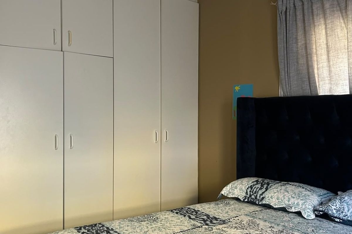 A bedroom featuring white built-in cupboards providing ample storage space.