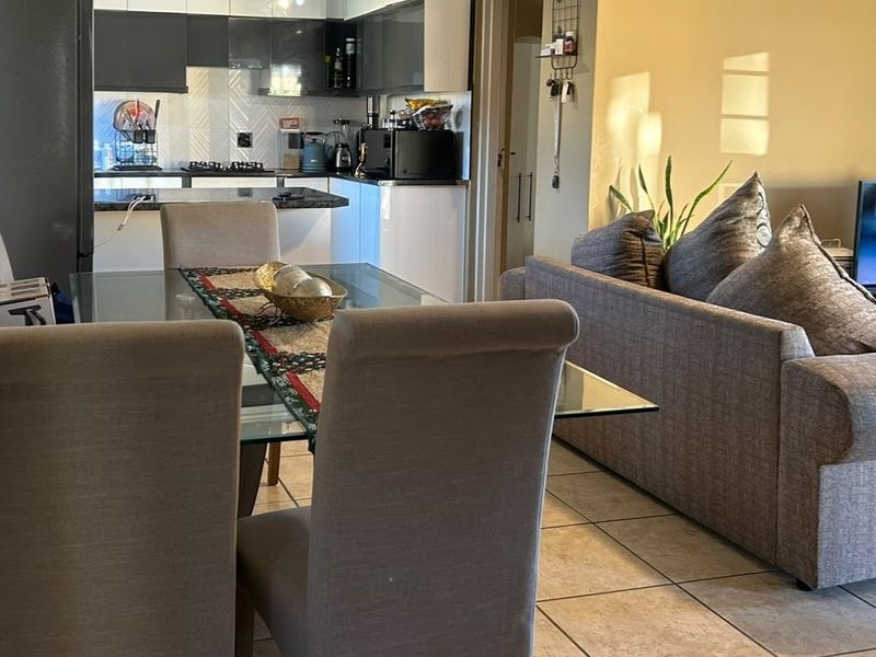 Open-plan living and dining area featuring tiled flooring and a modern kitchen with built-in cabinetry and a gas hob.