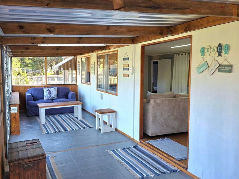 A covered patio area featuring exposed timber rafters, a corrugated metal roof, and tiled flooring, providing a seamless transition to the interior living space.