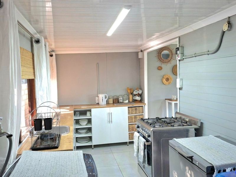 Functional kitchen featuring a gas stove, built-in cabinetry, stainless steel sink, and tiled flooring with exposed electrical conduit detailing.