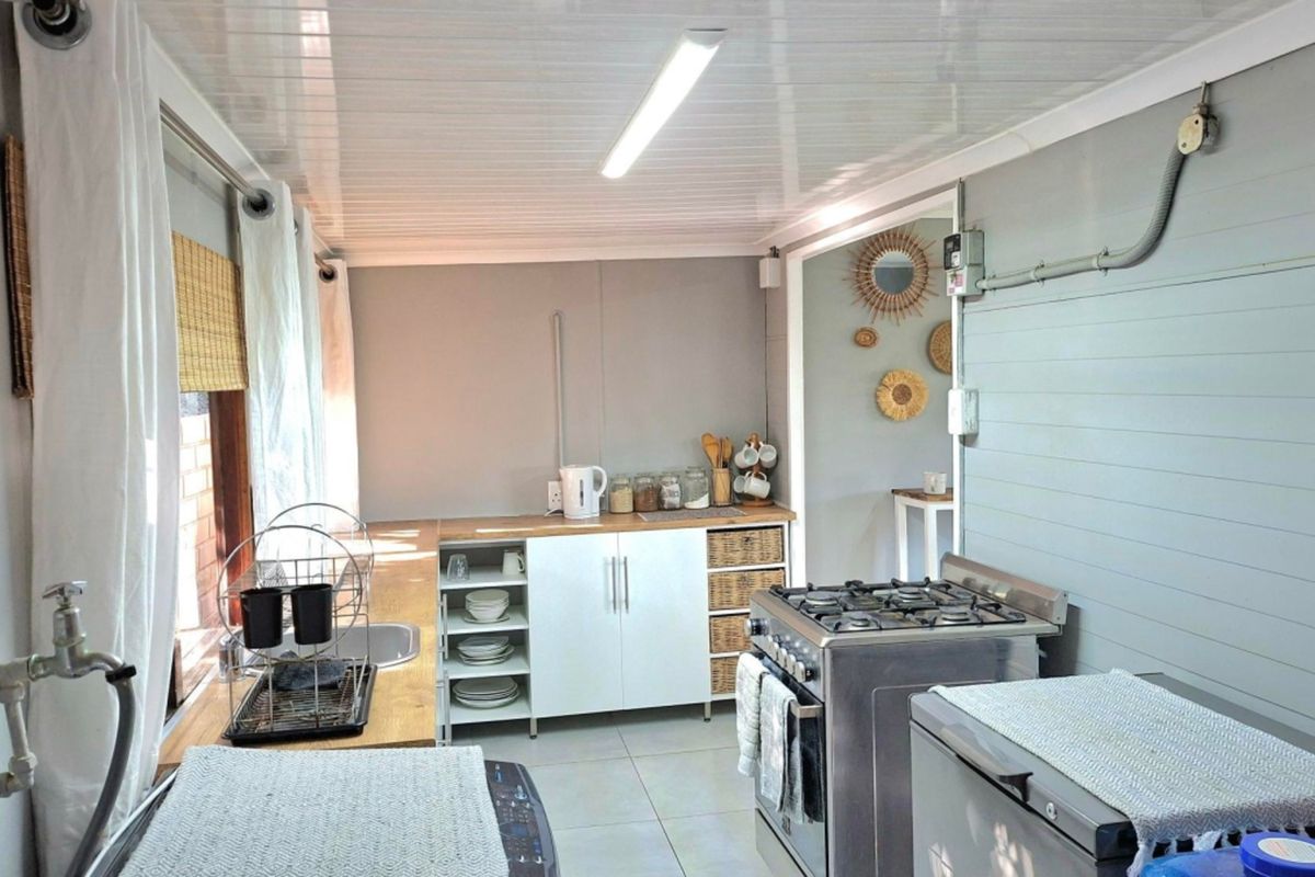Functional kitchen featuring a gas stove, built-in cabinetry, stainless steel sink, and tiled flooring with exposed electrical conduit detailing.