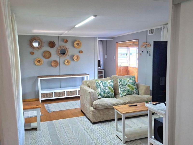 A comfortable living room featuring timber flooring and a bright, open layout with access to an adjoining sunroom area.