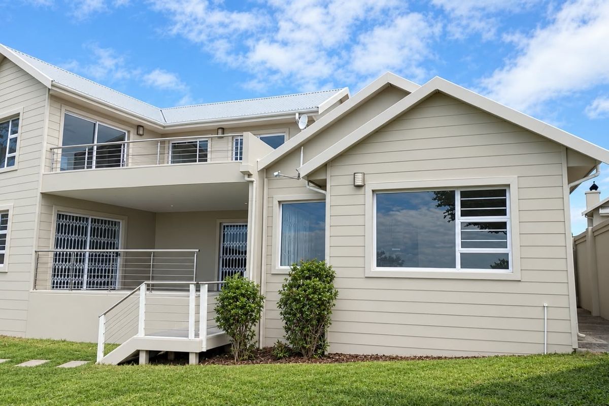 Rear view of a modern townhouse featuring a spacious balcony, clean exterior cladding, and well-maintained garden area.
