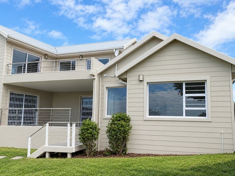 Rear view of a modern townhouse featuring a spacious balcony, clean exterior cladding, and well-maintained garden area.