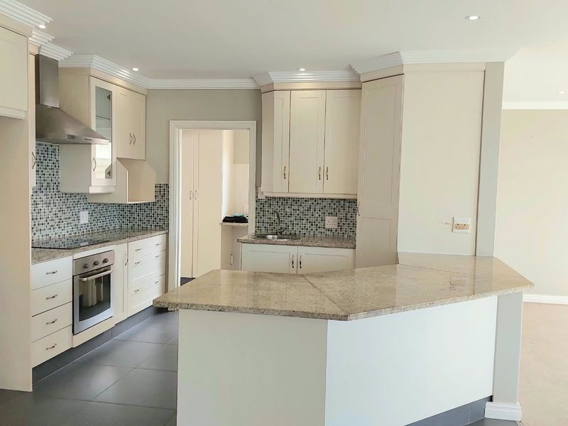 Modern kitchen featuring granite countertops, mosaic tile backsplash, built-in oven, electric hob, and a functional breakfast bar layout.