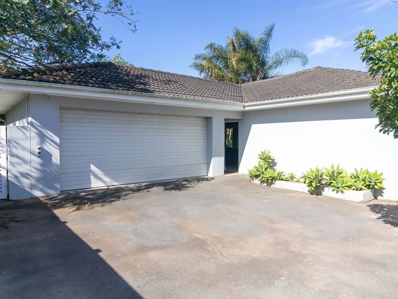 Exterior view of a single garage with a concrete driveway, tiled roof, and side access gate.