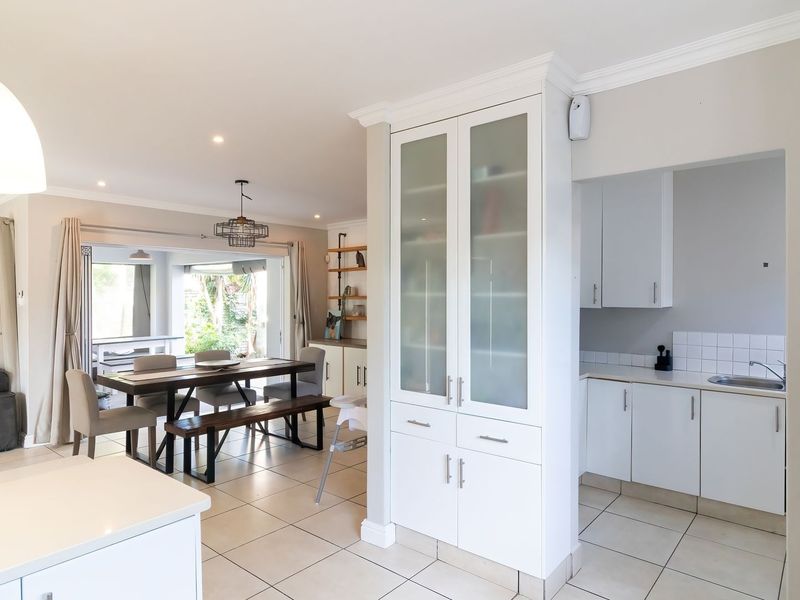 Spacious open-plan living and dining area featuring tiled floors, built-in cabinetry, and seamless flow to an outdoor patio through large sliding glass doors.