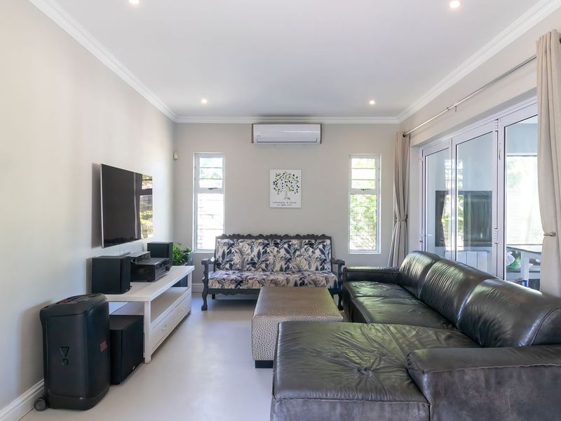 A bright and well-maintained living room featuring recessed lighting, a split-system air conditioner, and large sliding glass doors providing access to the outdoors.