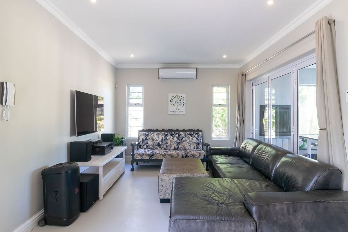 A bright and well-maintained living room featuring recessed lighting, a split-system air conditioner, and large sliding glass doors providing access to the outdoors.