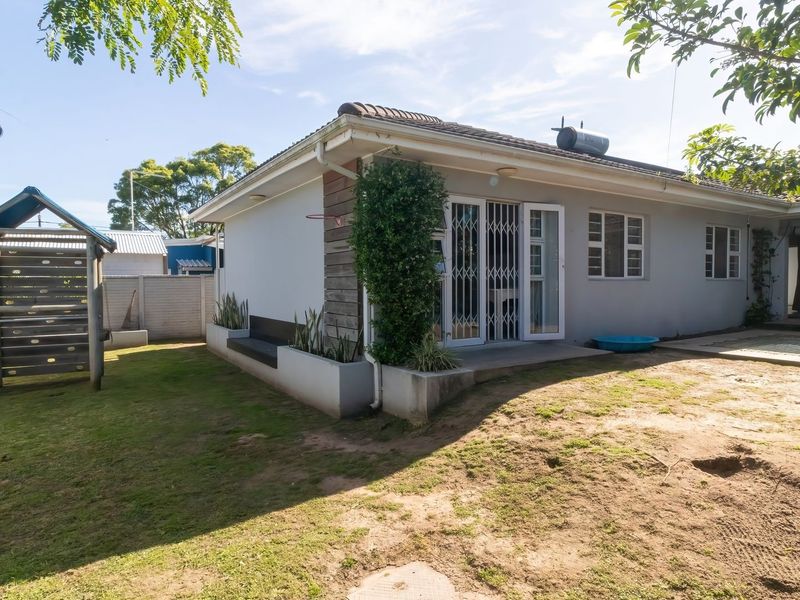 Rear view of the house featuring a concrete patio, security gates, built-in planter boxes, and a solar geyser installed on the tiled roof.
