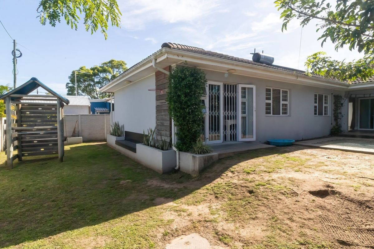 Rear view of the house featuring a concrete patio, security gates, built-in planter boxes, and a solar geyser installed on the tiled roof.