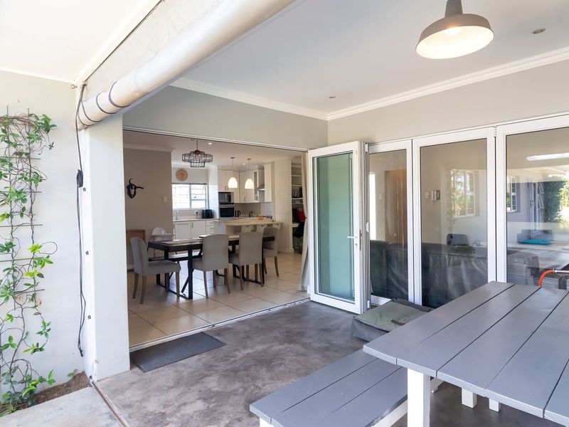 Covered patio area featuring concrete flooring and bi-fold doors providing seamless access to the open-plan interior living and dining space.