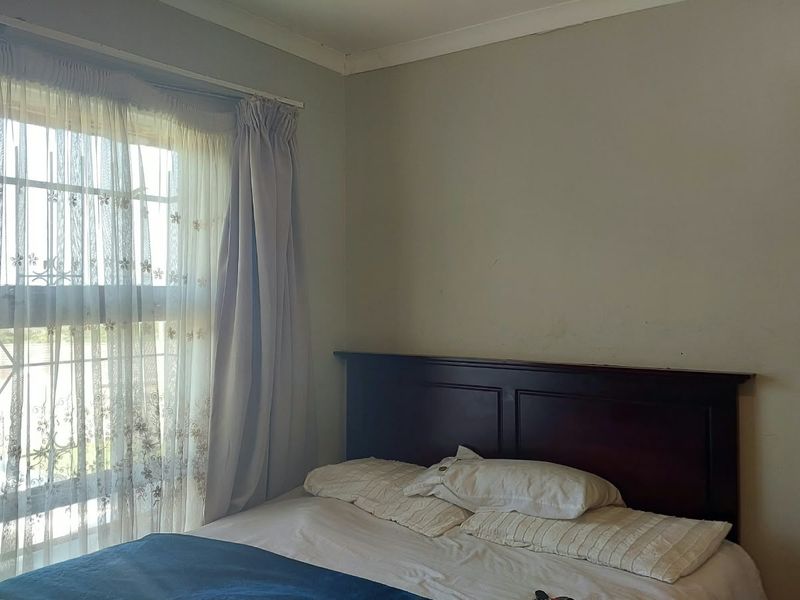 A standard bedroom featuring a large window with security bars and neutral wall finishes.
