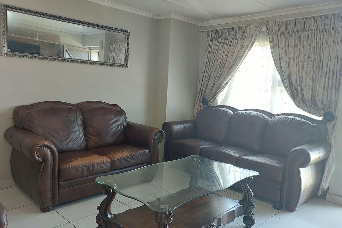 A living room featuring tiled flooring and natural light through window curtains, providing a functional space for relaxation.