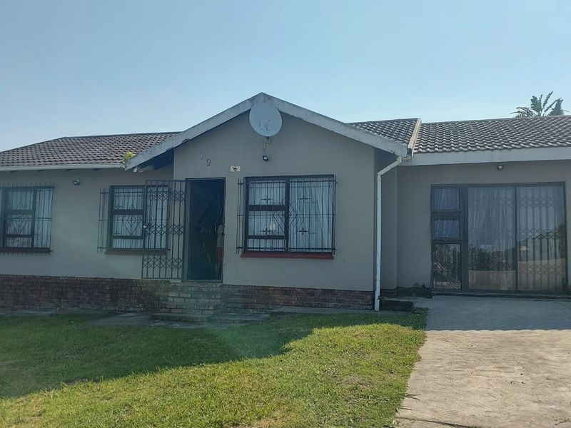 Front elevation of a single-story house featuring a tiled roof, brick base, security bars on windows, and a concrete driveway.